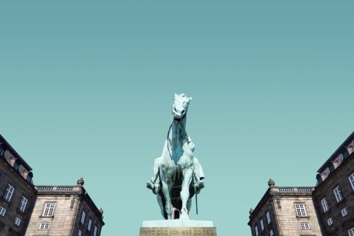 white horse statue near houses under blue sky