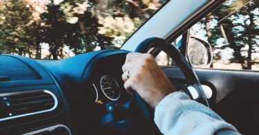 person holding black vehicle steering wheel driving
