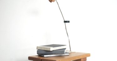 stack of notebooks and vase with dry rose placed on wooden table