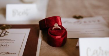 red box with golden ring placed on table with invitation cards (Jewelry)