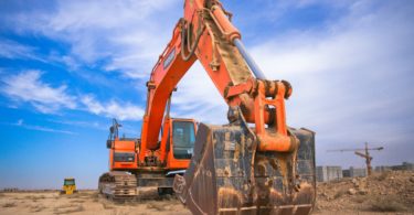 low angle photography of orange excavator under white clouds