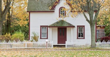 white and red wooden house with fence