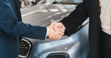 shaking hands over car
