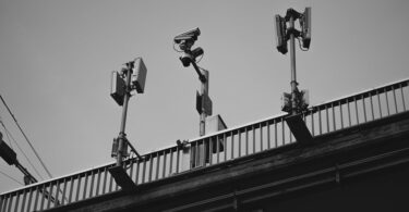 grayscale photo of a cctv camera and solar lights on steel railing Solar Lights