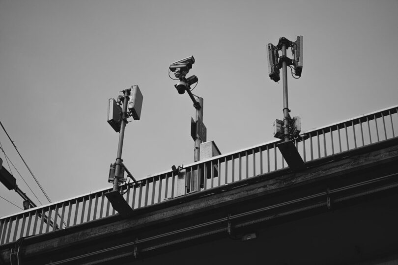 grayscale photo of a cctv camera and solar lights on steel railing Solar Lights