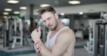 serious male athlete standing in gym and looking at camera