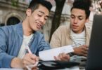 positive asian student doing homework with partner