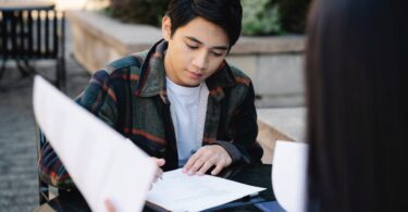 photo of a man in a white inner shirt studying