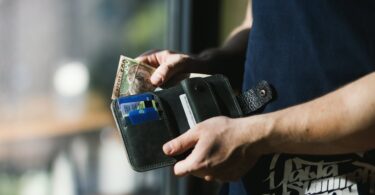 photograph of person holding black leather wallet with money
