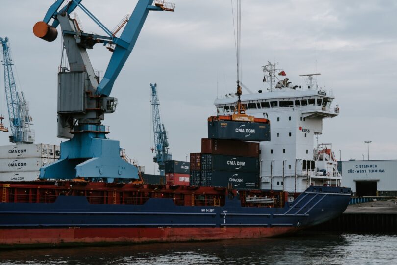 blue and red cargo ship with crane