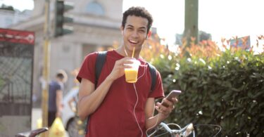 happy young man using smartphone on street