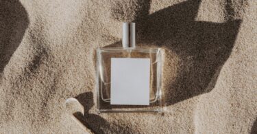 clear glass perfume bottle on white sand