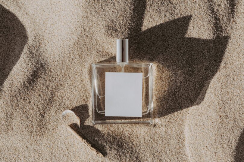 clear glass perfume bottle on white sand