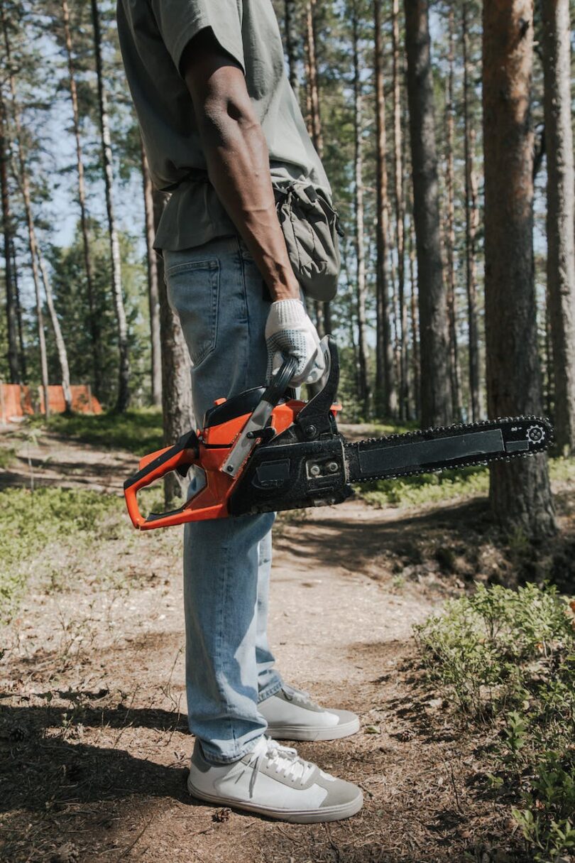 a person in denim pants holding a chainsaw