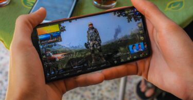 crop faceless man playing video game on smartphone