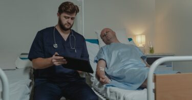 doctor sitting beside a man lying on the hospital bed