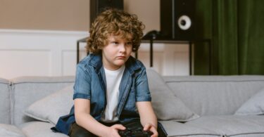 a boy playing video games while sitting on a sofa