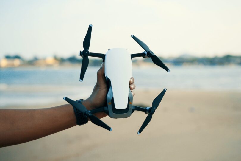 person holding white and black quadcopter drone