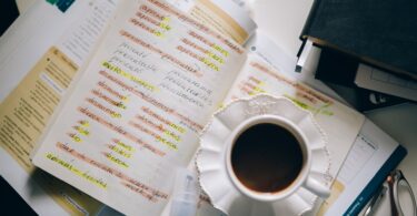 a cup of black coffee on a notebook with notes of foreign language with translation