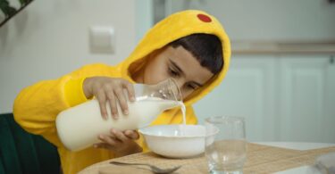 boy in yellow pajama holding a bottle of milk
