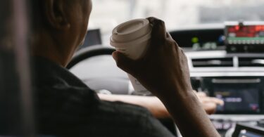 faceless driver drinking coffee while driving car