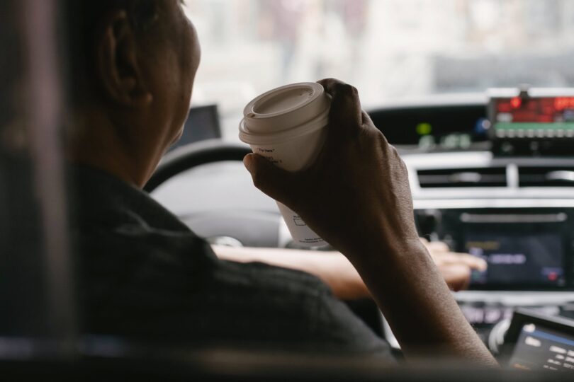 faceless driver drinking coffee while driving car