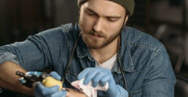 man drawing a tattoo on the knee