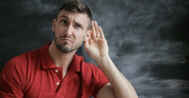 man in red polo shirt sitting near chalkboard
