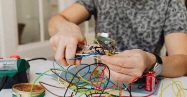 photo of a person s hands cutting a green cable